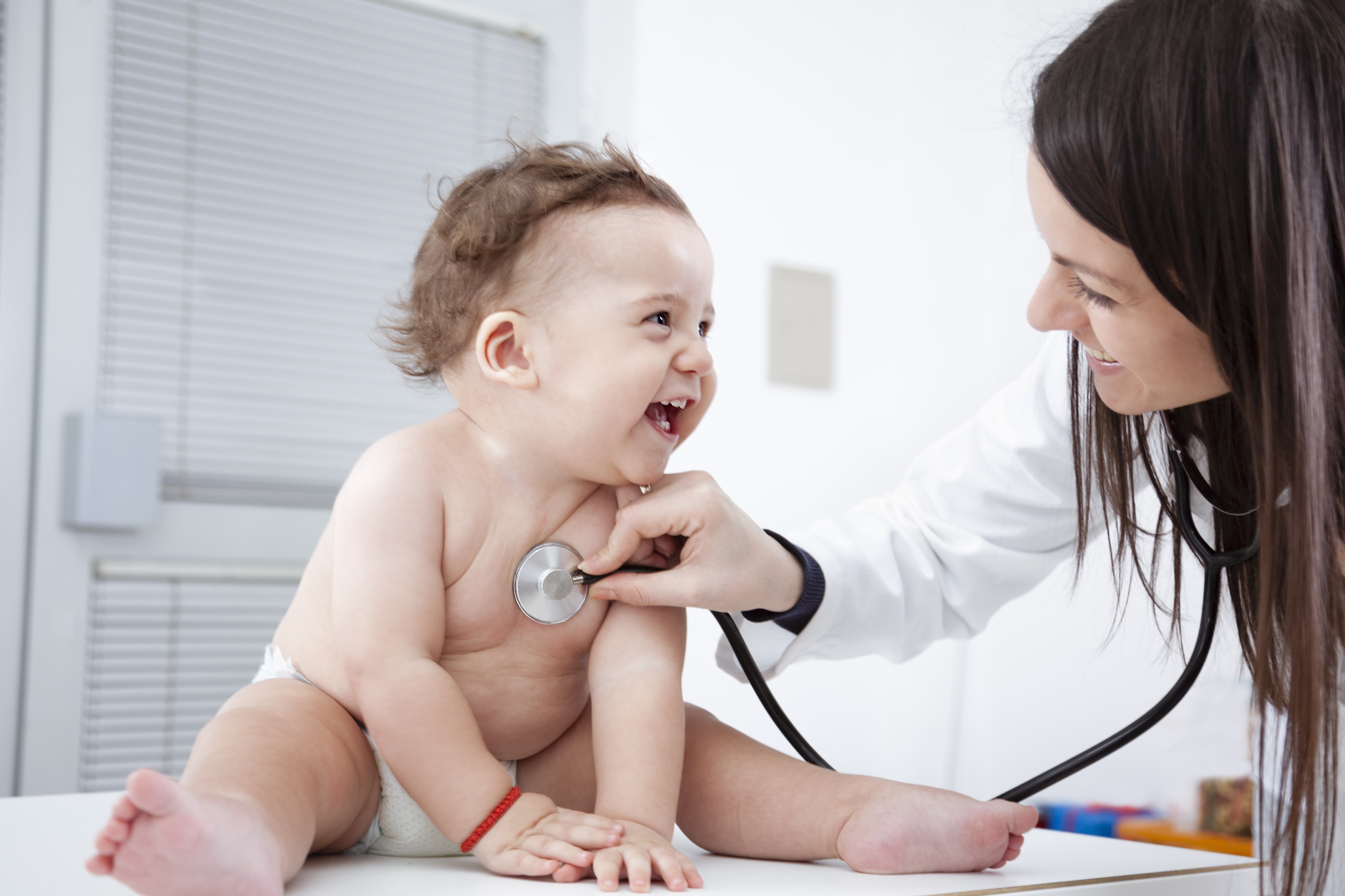 Child listening to baby's beats leaning against her pregnant mother's belly.